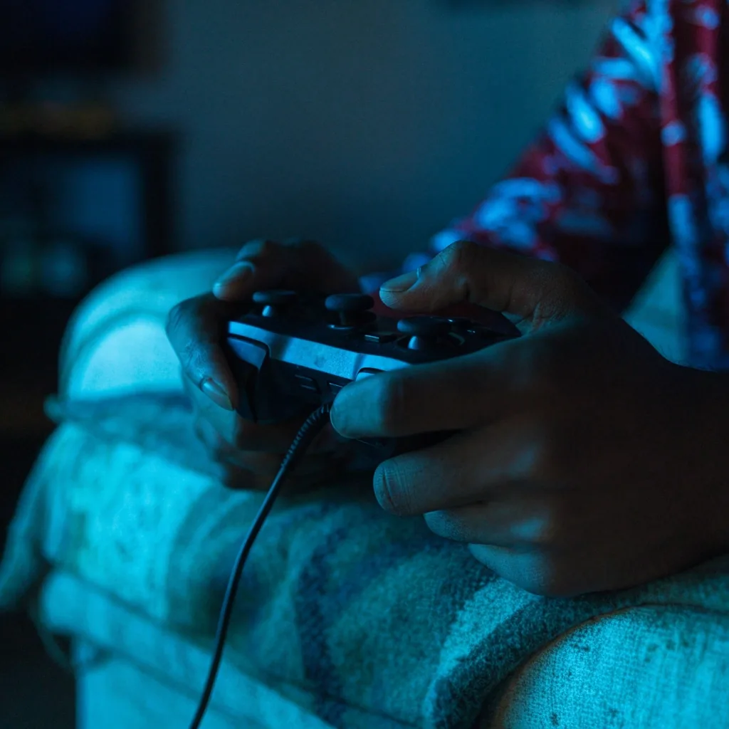 Mãos digitando em teclado escuro sob luz fria de tela em mesa de trabalho